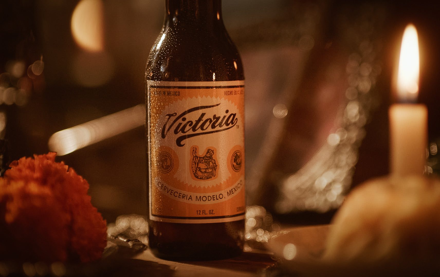A bottle of Victoria on table near candle.